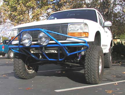 1984 Ford Bronco - This white Ford Bronco features a prominent blue custom bumper with large auxiliary lights.