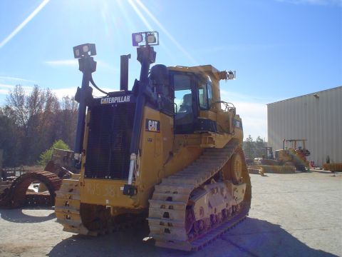 1966 International School Bus - A yellow Caterpillar bulldozer sits in a lot under a bright blue sky, with another machine in the distance.