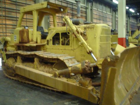 1966 International School Bus - A yellow bulldozer is shown from a three-quarter front view inside a building.