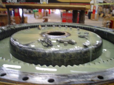 1966 International School Bus - A large gear assembly, possibly from heavy machinery, sits in a pool of fluid. Text in the background indicates 'CAT'.
