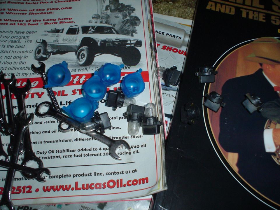 Wrenches, blue bulb covers, and light bulbs on top of automotive literature