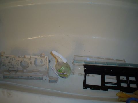 1984 Ford Bronco - Automotive dashboard parts are cleaned in a bathtub with a spray bottle nearby.