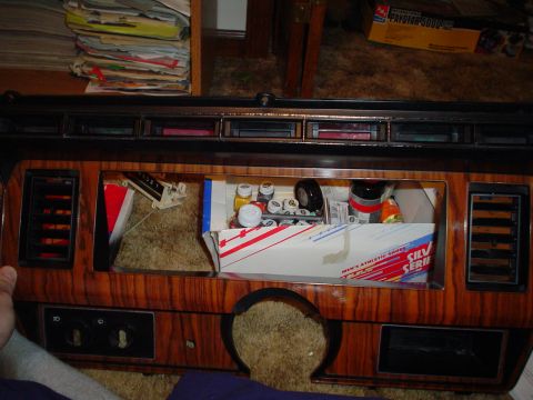 1984 Ford Bronco - The dashboard of a vehicle is shown with a cubby containing various items and a box labeled 'SILV SERIES MEN'S ATHLETIC SHOES'.