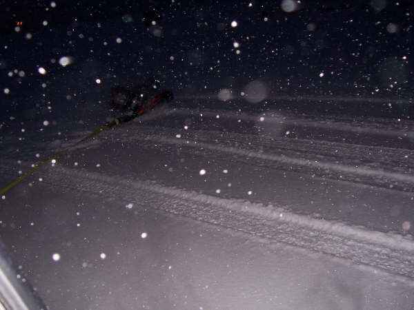 Person being pulled by a rope in a snowy landscape at night