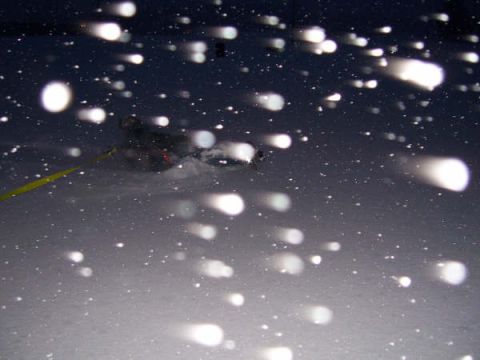 1994 Ford Bronco - A vehicle navigates through a snowy landscape, illuminated by its headlights and falling snow.