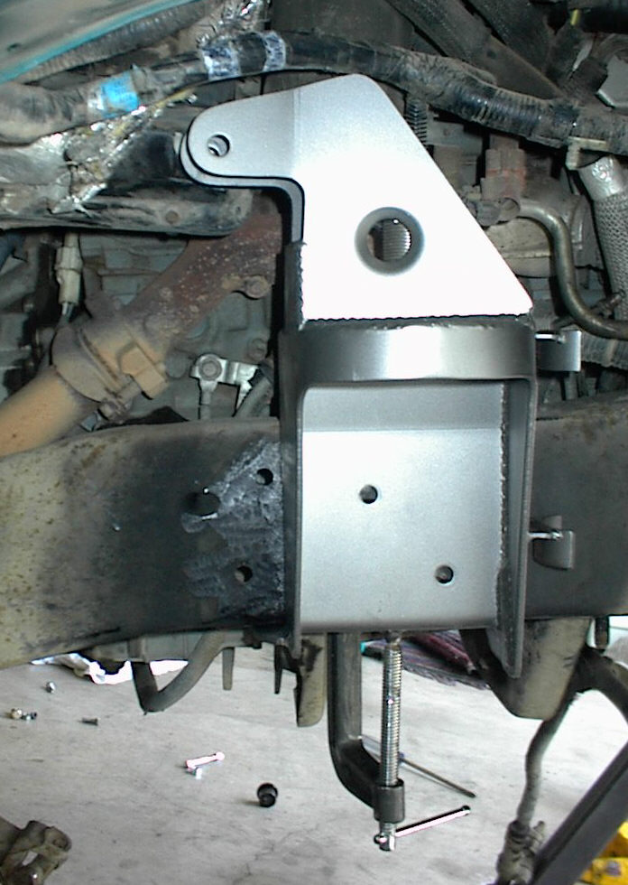 Custom metal bracket clamped to a vehicle frame near engine components