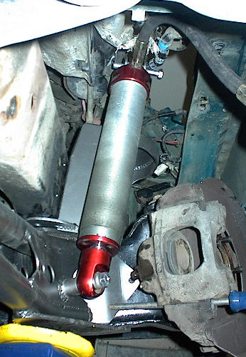 1984 Ford Bronco - Detail of a vehicle's suspension and braking system, showing a shock absorber and caliper.