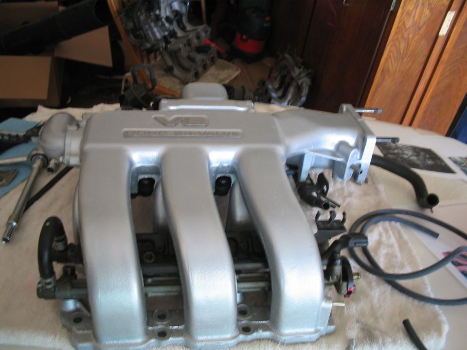 Refinished V6 intake manifold and parts laid out on a workbench