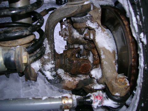 2003 Jeep TJ - This close-up shows the front axle assembly of a Jeep TJ, covered in snow and showing signs of rust.