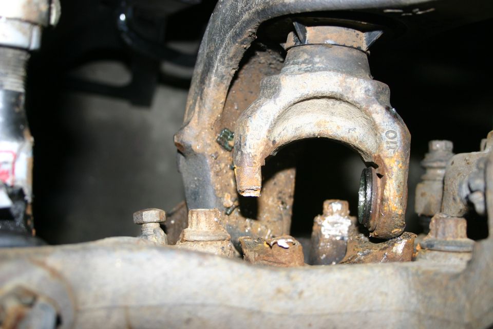 Close-up of heavily rusted suspension parts, including bolts and a bracket