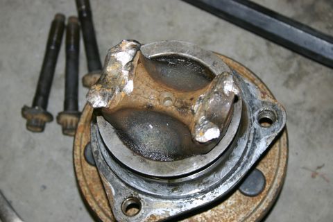 2003 Jeep TJ - A close-up view of a damaged axle hub, with four bolts lying next to it.