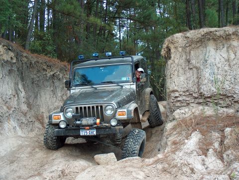2004 Jeep Wrangler - A Jeep Wrangler TJ is shown off-roading on a challenging dirt path, demonstrating its capabilities.