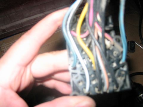 1991 Ford Bronco - Wiring harness connector with multiple colored wires being held by a hand.