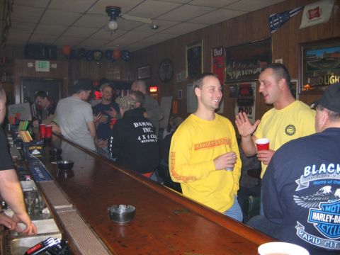 1977 Ford F-150 - A group of people are socializing at a bar, with some wearing branded apparel.