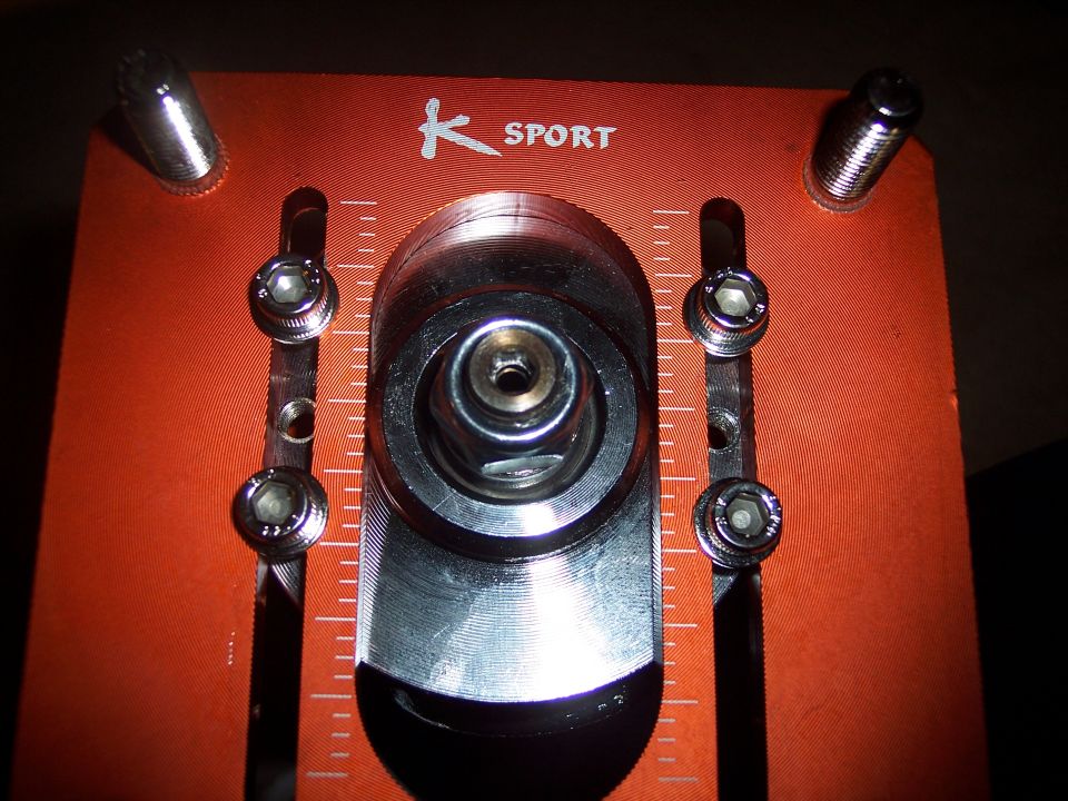 Close-up of an orange K-Sport adjustable strut mount with hex bolts and measurement markings