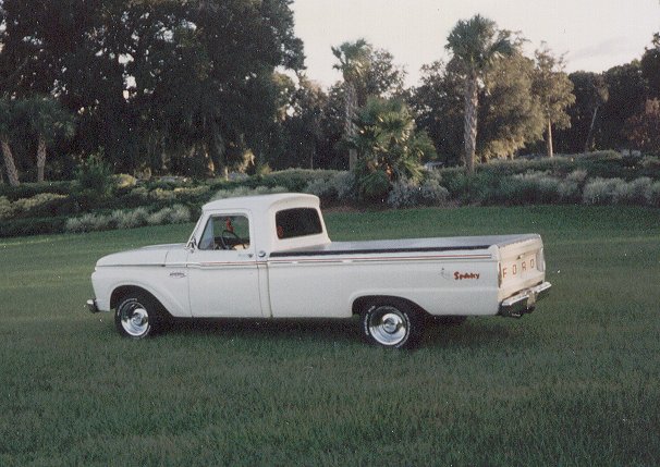 White 1965 Ford F-100 pickup truck, side view, with "Sporty" badging on the bed