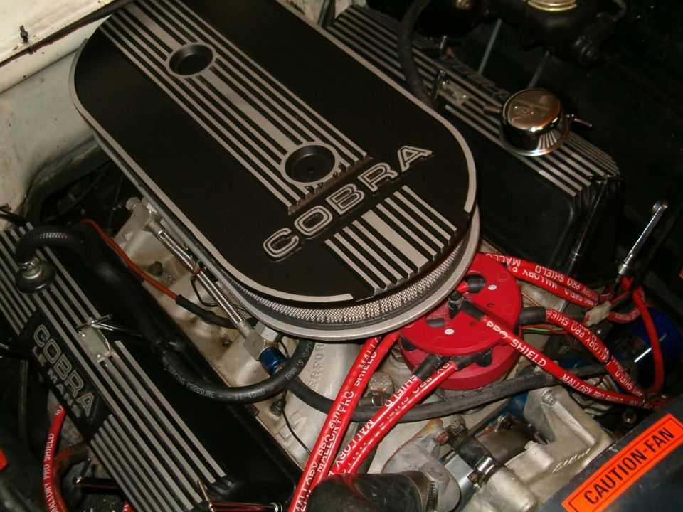 Engine bay with black Cobra valve covers and red spark plug wires. A "SUPERMOTORS.NET" watermark is visible