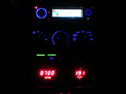 1996 Ford Probe - The dashboard of a car features illuminated blue controls and red digital gauges displaying RPM and water temperature.