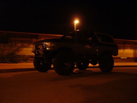 1989 Ford Bronco - This lifted Ford Bronco is parked at night under a streetlamp.