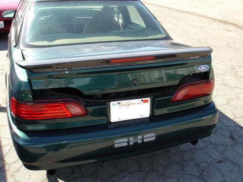 1993 Ford Taurus - Rear view of a green 1993 Ford Taurus sedan, showing its taillights, spoiler, and California license plate.