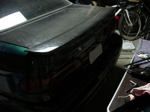1993 Ford Taurus - The rear of a car is shown with a carbon fiber spoiler and a blank license plate, parked indoors.