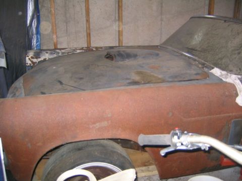 1956 Ford Thunderbird - A heavily rusted car's front end is visible, partially covered, in a dimly lit garage.