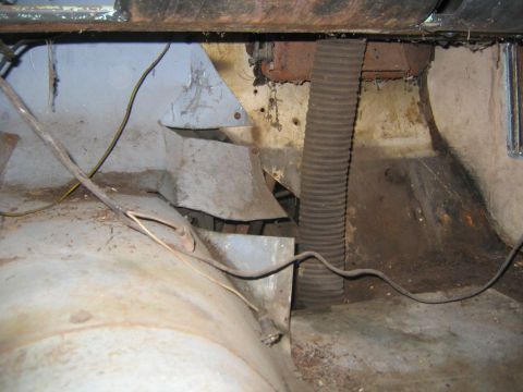 1956 Ford Thunderbird - The interior floor of a vehicle shows a corrugated duct and wiring, with signs of rust and wear.