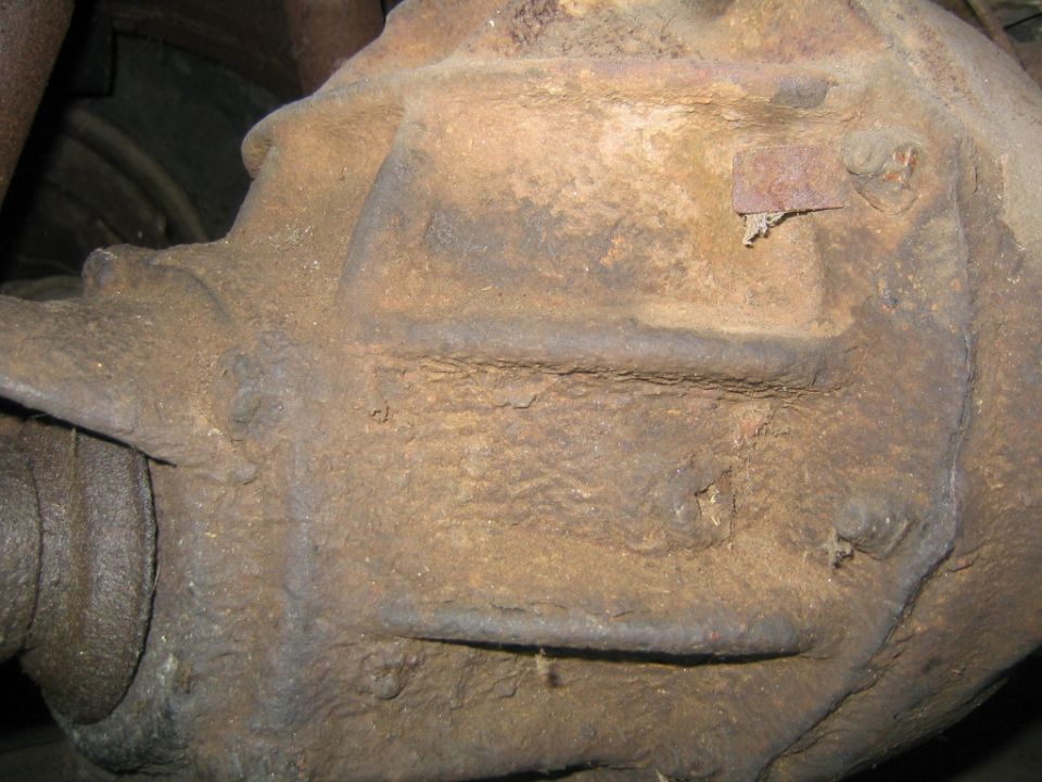 Close-up of a heavily rusted rear differential housing with corroded ID tag