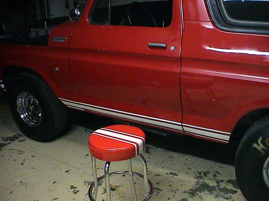 Red 1979 Ford Bronco side view with racing stripe and chrome wheels