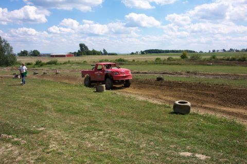 1979 Ford F-150 - A red pickup truck navigates a muddy track under a partly cloudy sky.
