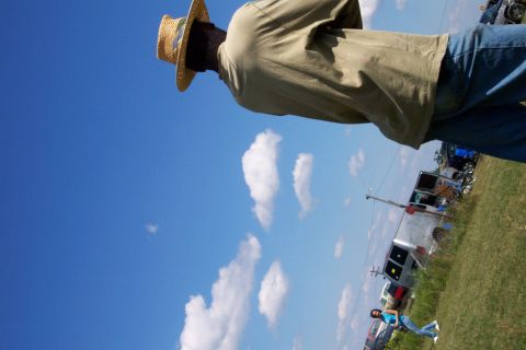1979 Ford F-150 - A person in a straw hat stands in front of a sunny sky with clouds, with several vehicles visible in the distance and a Supermotors logo at…