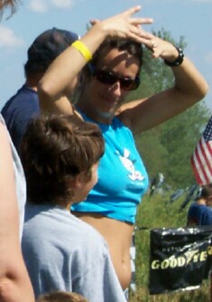1979 Ford F-150 - A woman adjusts her hair while standing outdoors with other people and a partial American flag visible.