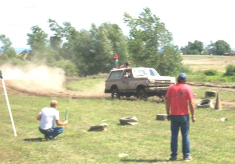 1979 Ford F-150 - A Ford Bronco navigates a muddy course during an event, with spectators observing.