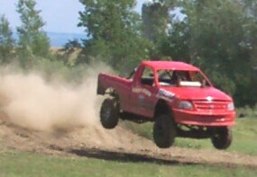 1979 Ford F-150 - A red pickup truck soars through the air, leaving a trail of dust behind it.