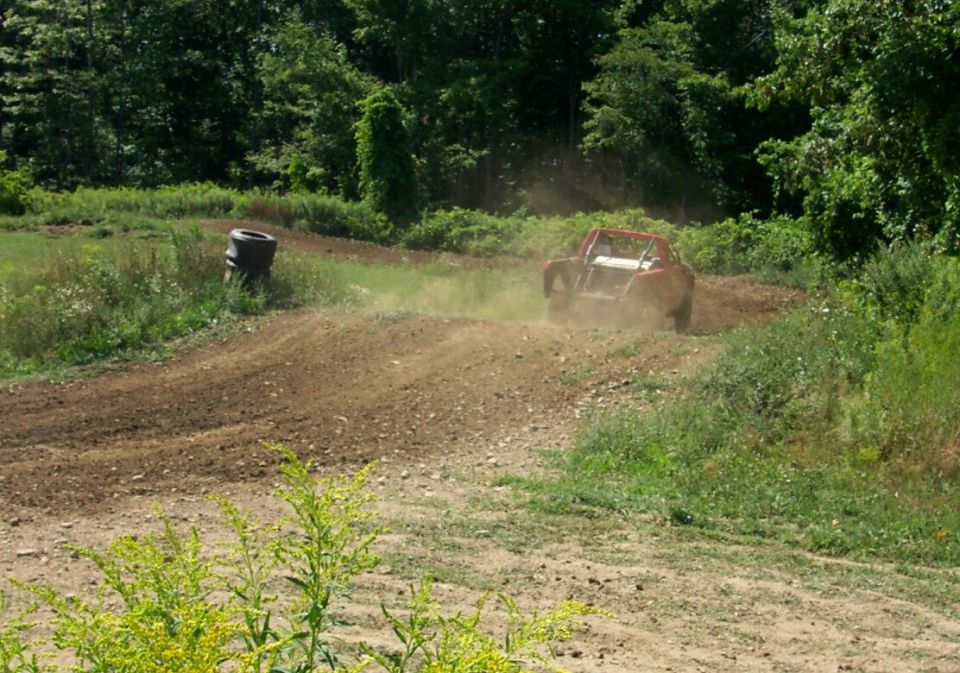 Red off-road buggy kicking up dust on a dirt track