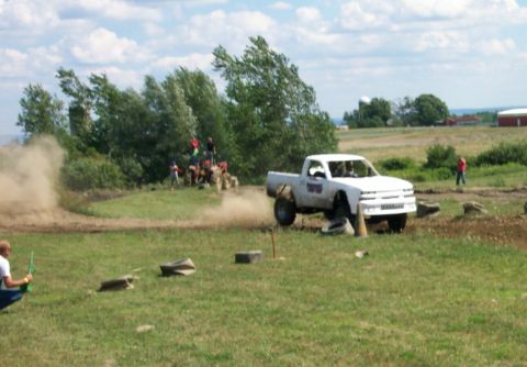 1979 Ford F-150 - A white pickup truck with oversized tires maneuvers through an outdoor obstacle course, creating a cloud of dust.