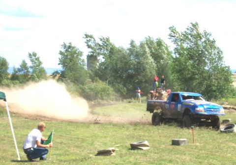 1979 Ford F-150 - Pickup truck navigates a dusty off-road course with spectators watching.