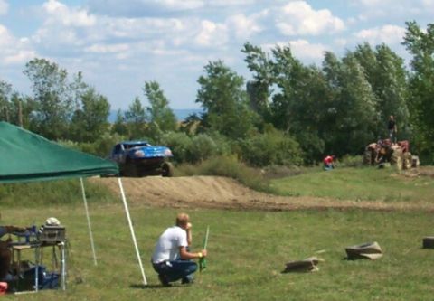 1979 Ford F-150 - An off-road event with a blue truck on a dirt track and spectators nearby.