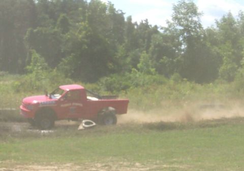 1979 Ford F-150 - A red pickup truck drives on a dirt track, creating a cloud of dust.