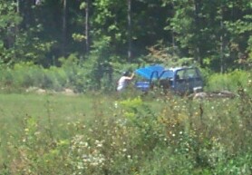 1979 Ford F-150 - A person washes a blue van in a field on a sunny day.