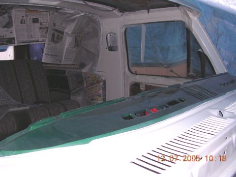 1978 Ford Bronco - The interior of a vehicle is covered in newspaper, with a green dashboard in the foreground.