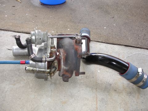 1989 Mazda MX-6 - A turbocharger assembly with blue and black hoses is shown resting on a concrete surface.