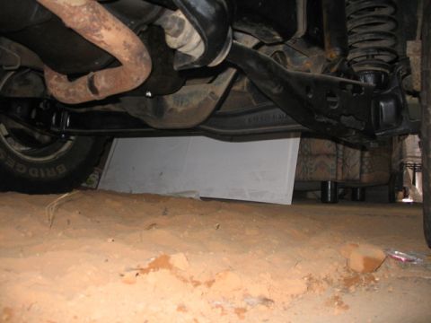 1981 Ford Bronco - A low-angle view reveals the undercarriage of a vehicle, with suspension and exhaust systems visible. Tire branding reads BRIDGE.