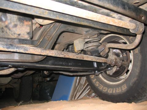 1981 Ford Bronco - The front suspension and tire of a 1981 Ford Bronco are visible from below.