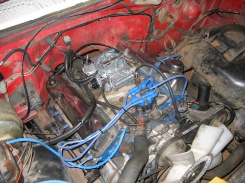 1981 Ford Bronco - Close-up view of a vehicle's engine bay, a carburetor and prominent blue spark plug wires.