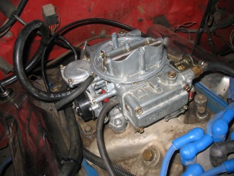 1981 Ford Bronco - Close-up of a Holley carburetor installed on an engine, with visible fuel lines and spark plug wires.