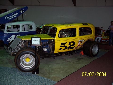 1987 Ford Bronco - A yellow sedan race car with number 52 is displayed next to another race car.
