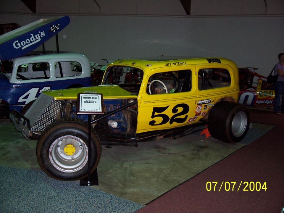 Yellow sedan race car with number 52, modified for racing with exposed engine and large tires