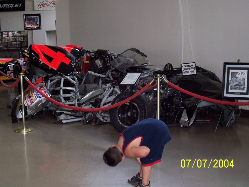 wrecked race car with number 44 on it, a kid is bending over in front of it