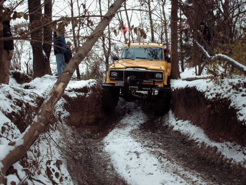 1977 Ford F-150 - Yellow Jeep Cherokee tackles a snowy off-road trail, showing its off-road capabilities.